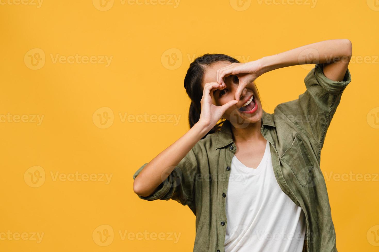 jovem asiática com expressão positiva, sorriso largo, vestida com roupas casuais e olhando para a câmera sobre fundo amarelo. feliz adorável feliz mulher alegra sucesso. conceito de expressão facial. foto