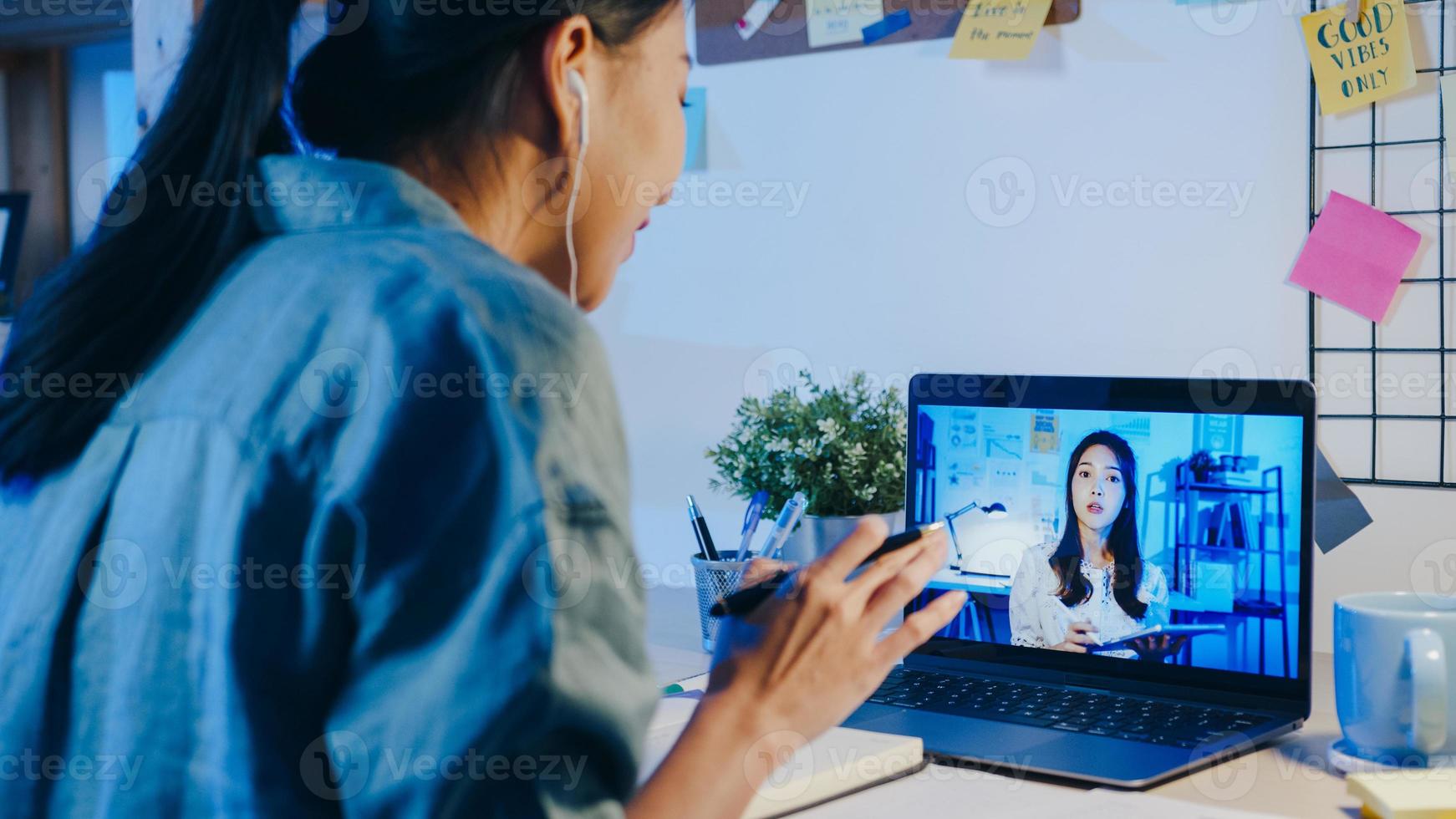 empresária asiática usando laptop conversa com colegas sobre o plano de uma reunião de videochamada na sala de estar. trabalho em casa sobrecarregada à noite, trabalho remoto, distanciamento social, quarentena para coronavírus. foto