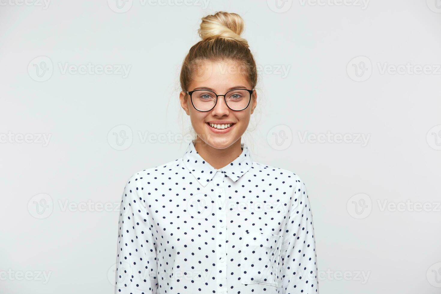 retrato do alegre lindo jovem mulher com pão desgasta polca ponto camisa e óculos sente confiante e parece para a Câmera isolado sobre branco fundo foto