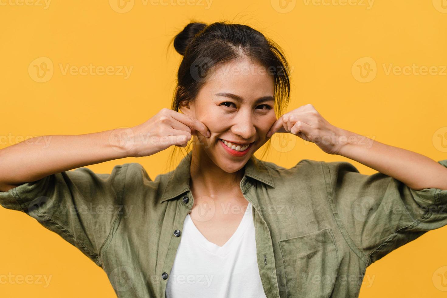 jovem asiática com expressão positiva, sorriso largo, vestida com roupas casuais e olhando para a câmera sobre fundo amarelo. feliz adorável feliz mulher alegra sucesso. conceito de expressão facial. foto