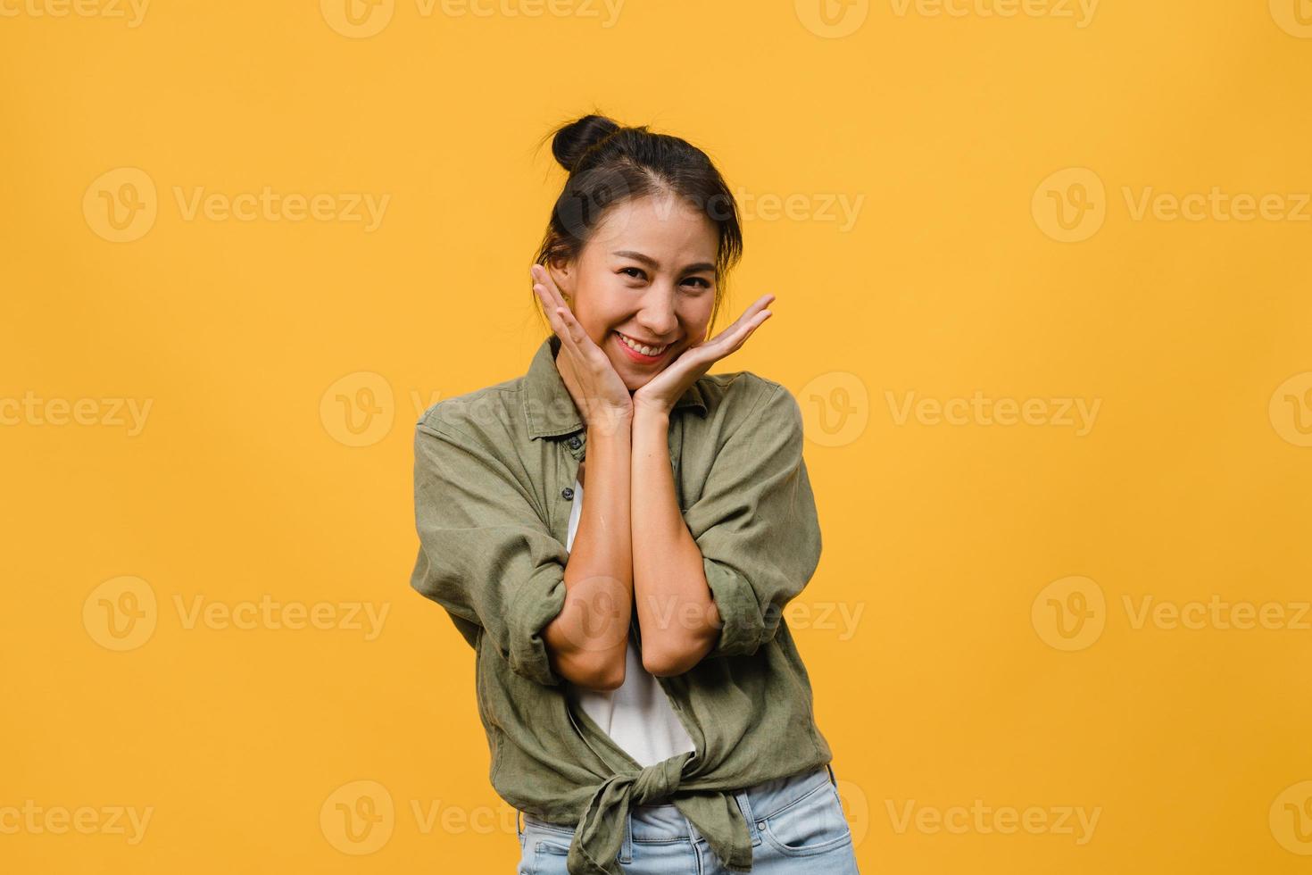 jovem asiática com expressão positiva, sorriso largo, vestida com roupas casuais e olhando para a câmera sobre fundo amarelo. feliz adorável feliz mulher alegra sucesso. conceito de expressão facial. foto