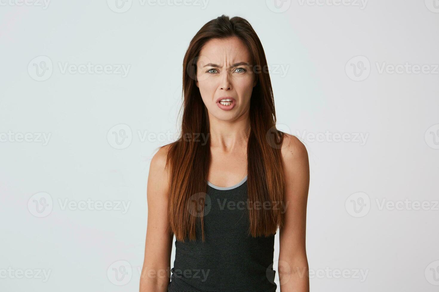 louco irritado jovem mulher com grandes cabelo parece furioso e discutindo isolado sobre branco fundo sente Bravo e olhando e Câmera foto