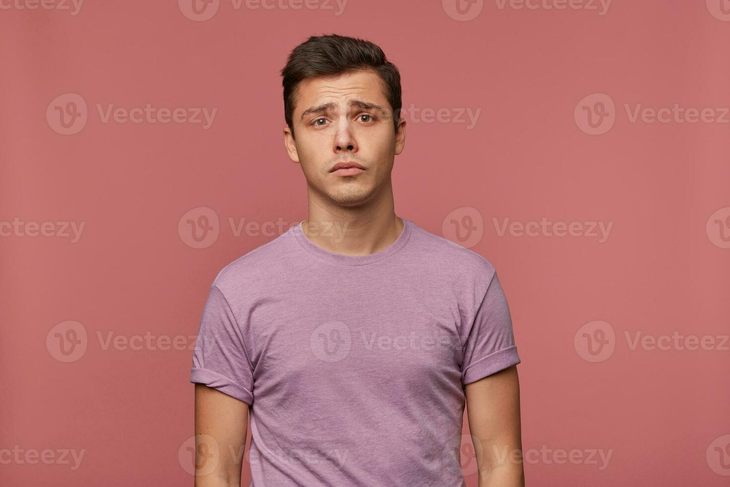 retrato do jovem atraente Garoto dentro em branco camiseta, carrinhos sobre Rosa fundo e parece triste e infeliz. foto