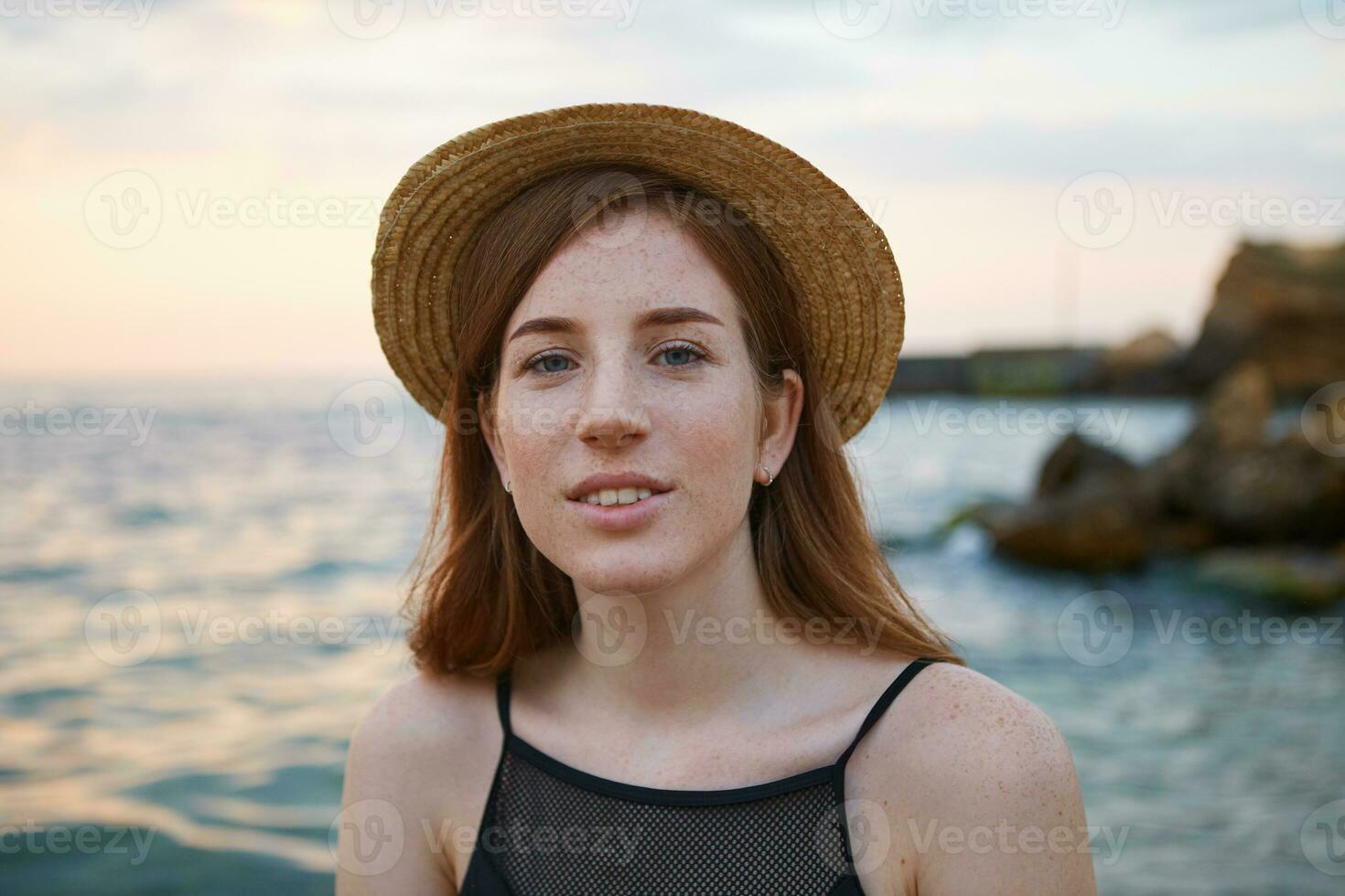 fechar acima do jovem gengibre fofa sardas mulher desgasta chapéu, sorrisos e calmante parece às a Câmera. parece sonhadoramente e feliz. foto