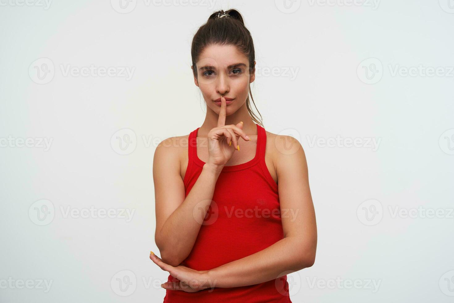 retrato do jovem misterioso fofa morena mulher desgasta dentro vermelho camiseta mostra silêncio gesto, por favor manter calma. carrinhos sobre branco fundo. foto