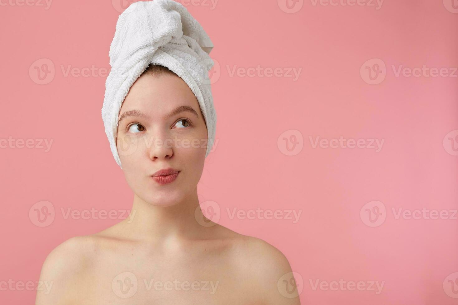 fechar acima do pensando jovem mulher com uma toalha em dela cabeça depois de banho, parece longe e sonhos sobre Novo vestir, carrinhos sobre Rosa fundo. foto