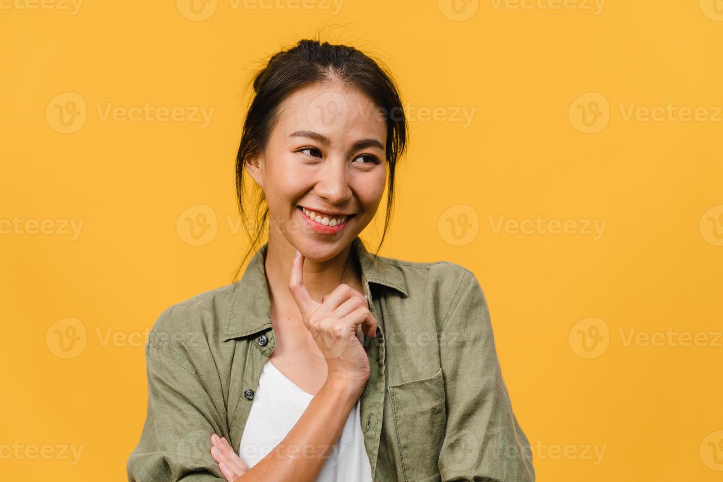 retrato de jovem asiática com expressão positiva, sorriso amplo, vestido com roupas casuais sobre fundo amarelo. feliz adorável feliz mulher alegra sucesso. conceito de expressão facial. foto