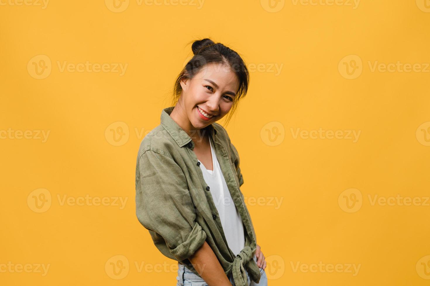 jovem asiática com expressão positiva, sorriso largo, vestida com roupas casuais e olhando para a câmera sobre fundo amarelo. feliz adorável feliz mulher alegra sucesso. conceito de expressão facial. foto