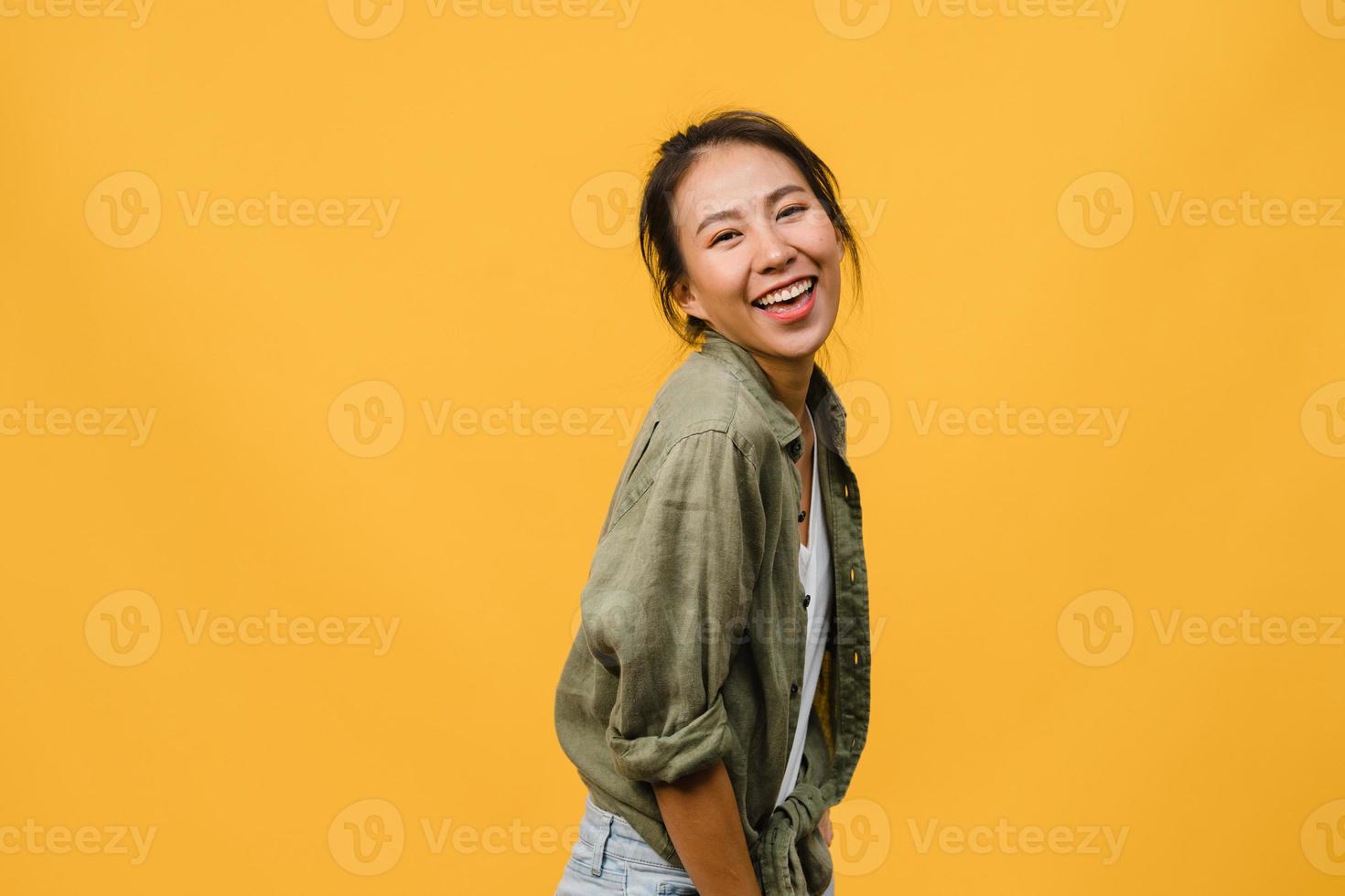 jovem asiática com expressão positiva, sorriso largo, vestida com roupas casuais e olhando para a câmera sobre fundo amarelo. feliz adorável feliz mulher alegra sucesso. conceito de expressão facial. foto