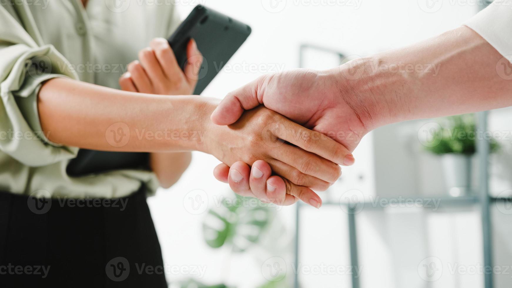 grupo multirracial de jovens criativos em smart casual wear, discutindo negócios, apertando as mãos e sorrindo em um escritório moderno. cooperação de parceiros, conceito de trabalho em equipe do colega de trabalho. foto