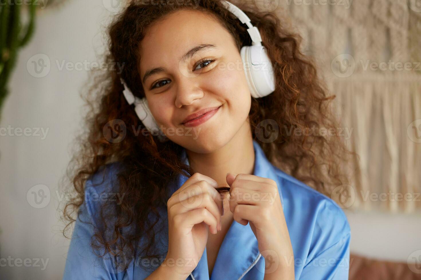 fechar acima do fofa ansioso encaracolado africano americano jovem mulher ouvindo favorito romântico música dentro fones de ouvido, sonhadoramente parece ausente, desfrutando a domingos manhã foto