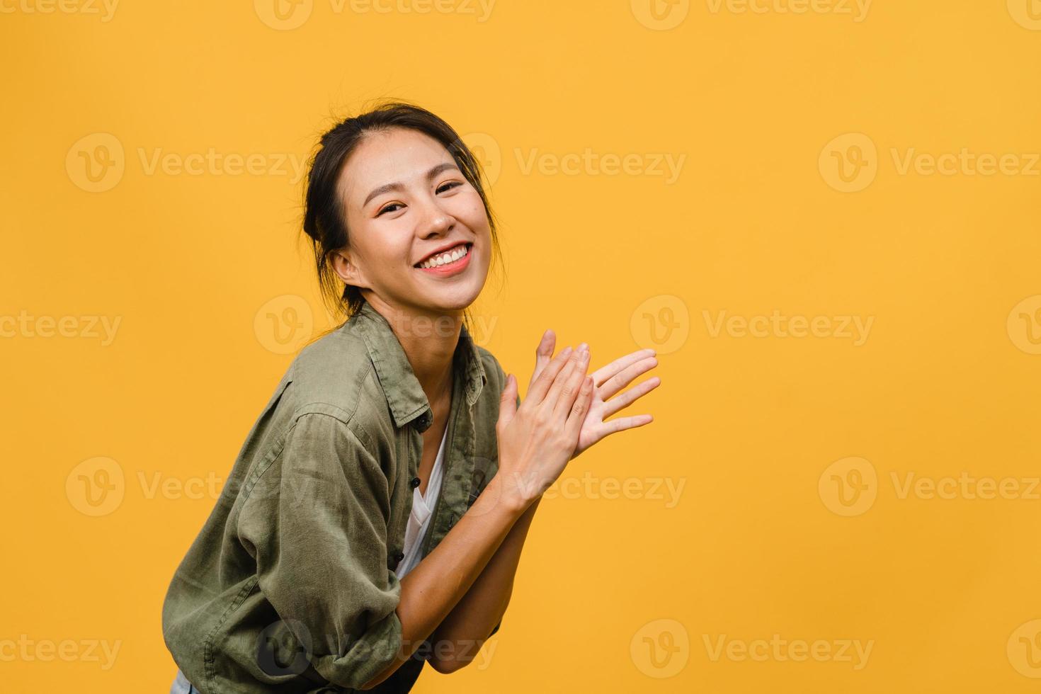 jovem asiática com expressão positiva, sorriso largo, vestida com roupas casuais e olhando para a câmera sobre fundo amarelo. feliz adorável feliz mulher alegra sucesso. conceito de expressão facial. foto