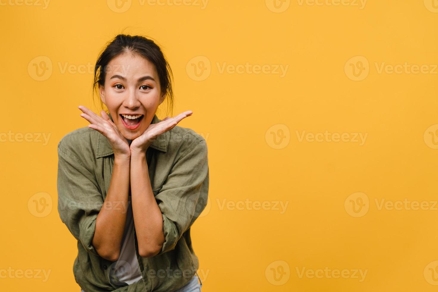 jovem asiática com expressão positiva, sorriso largo, vestida com roupas casuais e olhando para a câmera sobre fundo amarelo. feliz adorável feliz mulher alegra sucesso. conceito de expressão facial. foto