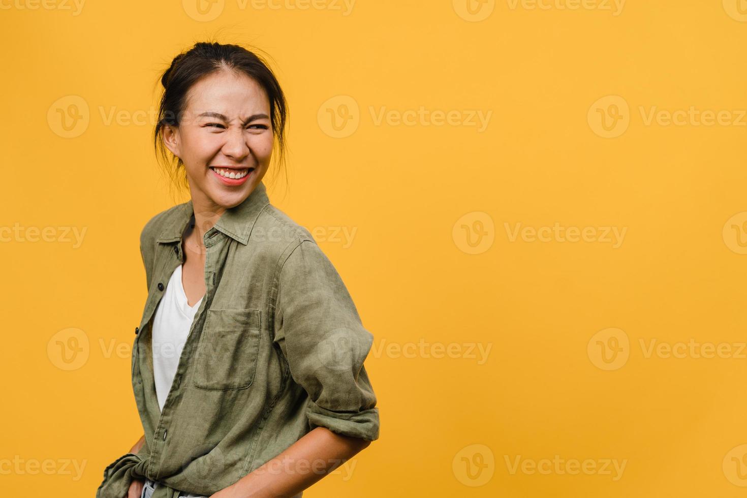 retrato de jovem asiática com expressão positiva, sorriso amplo, vestido com roupas casuais sobre fundo amarelo. feliz adorável feliz mulher alegra sucesso. conceito de expressão facial. foto