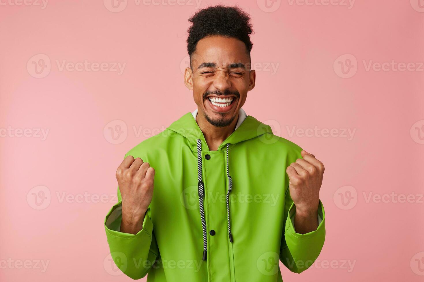 alegre jovem africano americano bonito cara carrinhos sobre Rosa fundo, cerrado dele punhos, amplamente sorridente e absolutamente feliz - ele Ganhou a loteria foto