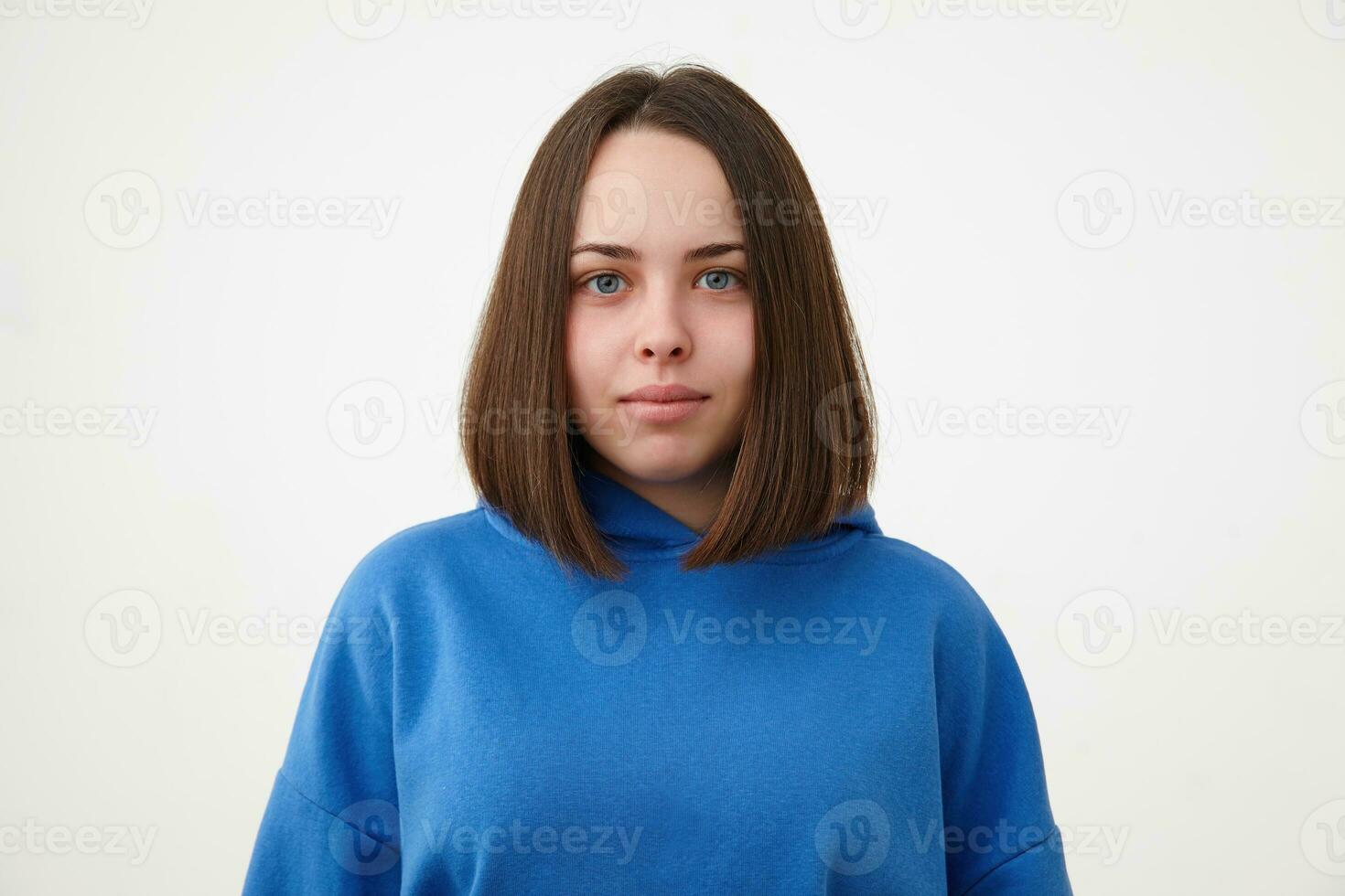 retrato do jovem lindo de olhos azuis morena senhora com curto corte de cabelo olhando positivamente às Câmera com luz sorriso, em pé sobre branco fundo dentro desportivo vestem foto