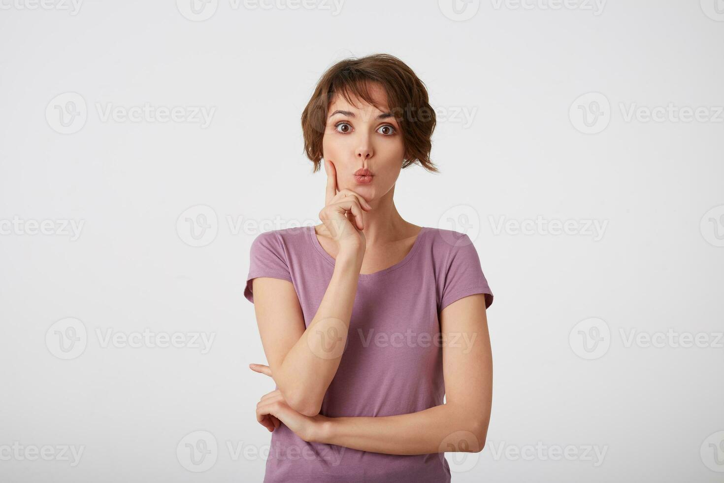 jovem atraente jovem cabelo curto mulher dentro em branco camiseta com uma surpreso expressão em dela face, isolado sobre branco muro. foto