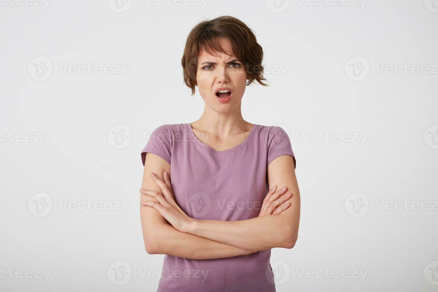 retrato do franzindo a testa descontente cabelo curto senhora dentro em branco camiseta, indignado de também baixo exame nota, carrinhos sobre branco parede com braços cruzado. foto