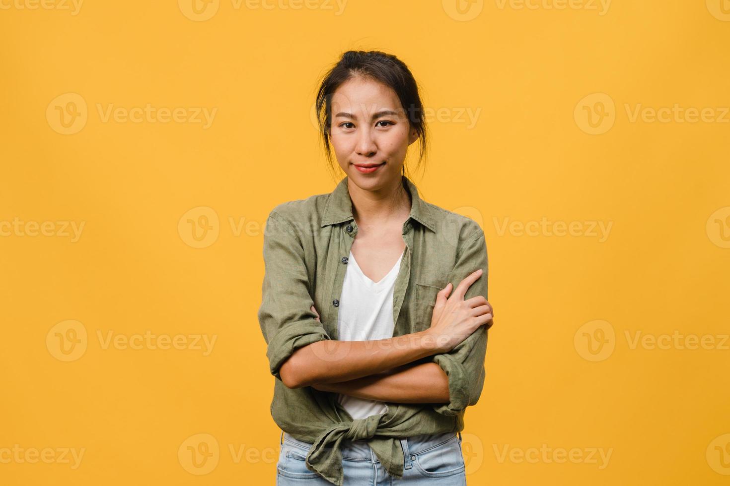 retrato de jovem asiática com expressão positiva, braços cruzados, sorriso largo, vestido com roupas casuais e olhando para a câmera sobre fundo amarelo. feliz adorável feliz mulher alegra sucesso. foto