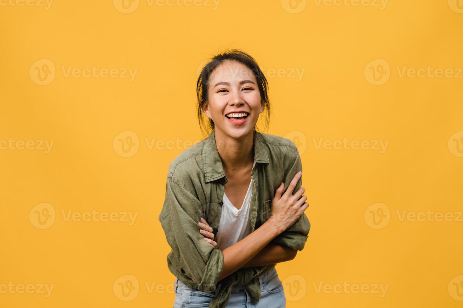 retrato de jovem asiática com expressão positiva, braços cruzados, sorriso largo, vestido com roupas casuais e olhando para a câmera sobre fundo amarelo. feliz adorável feliz mulher alegra sucesso. foto