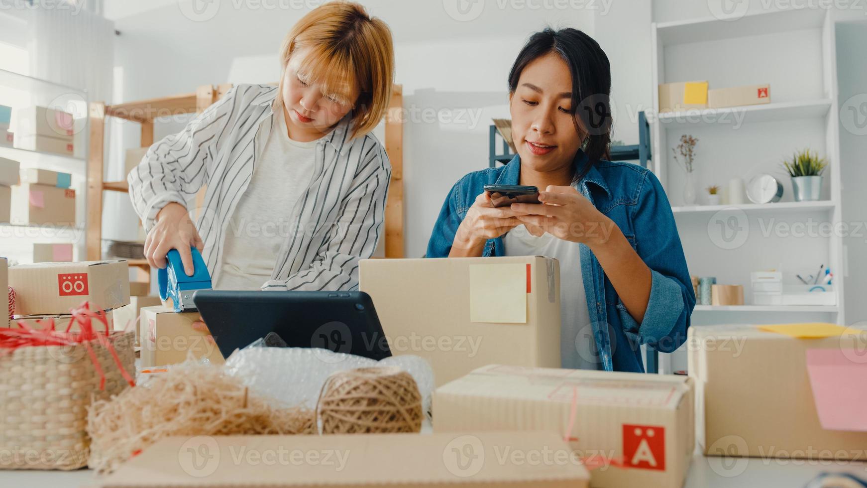 jovens empresárias da ásia usando telefone celular para receber o pedido de compra e verificar o produto no estoque trabalham no escritório em casa. proprietário de uma pequena empresa, entrega de mercado online, conceito freelance de estilo de vida. foto