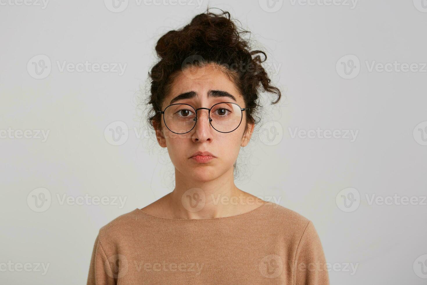 fechar-se do triste depressivo georgiano jovem mulher com encaracolado cabelo desgasta bege estacionar e óculos sente chateado e desapontado isolado sobre branco fundo foto