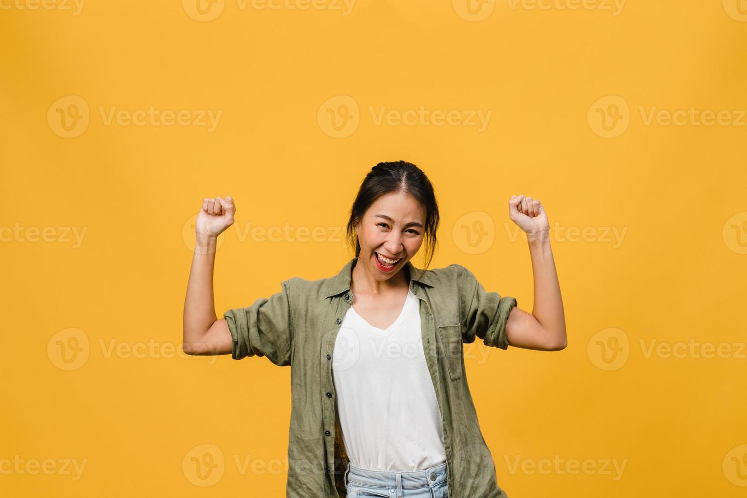 jovem asiática com expressão positiva, alegre e emocionante, vestida com um pano casual e olha para a câmera sobre fundo amarelo. feliz adorável feliz mulher alegra sucesso. conceito de expressão facial. foto