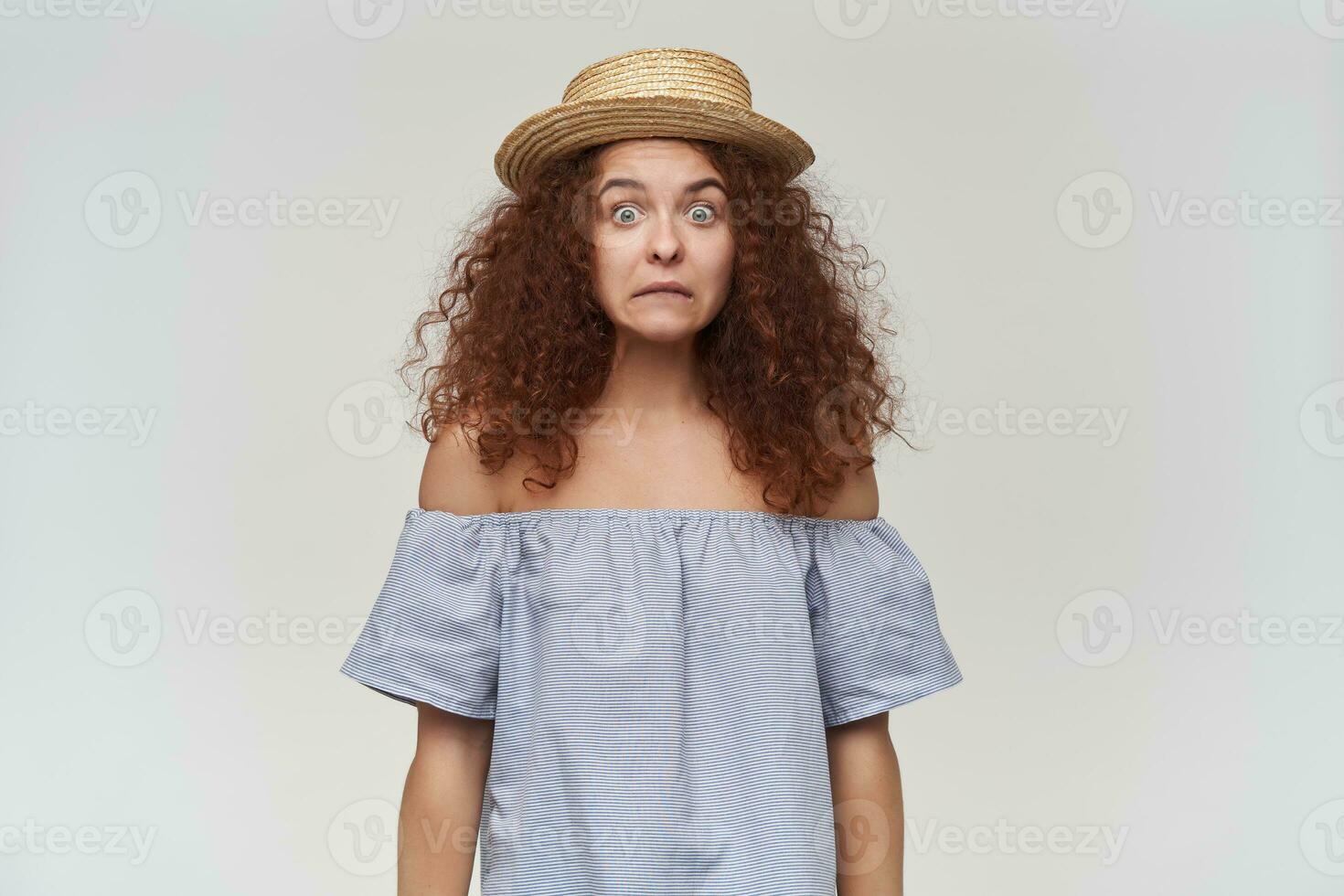 Adolescência garota, confuso olhando mulher com encaracolado gengibre cabelo. vestindo listrado ombros caídos blusa e chapéu. emocional conceito. confuso careta. assistindo às a Câmera, isolado sobre branco fundo foto