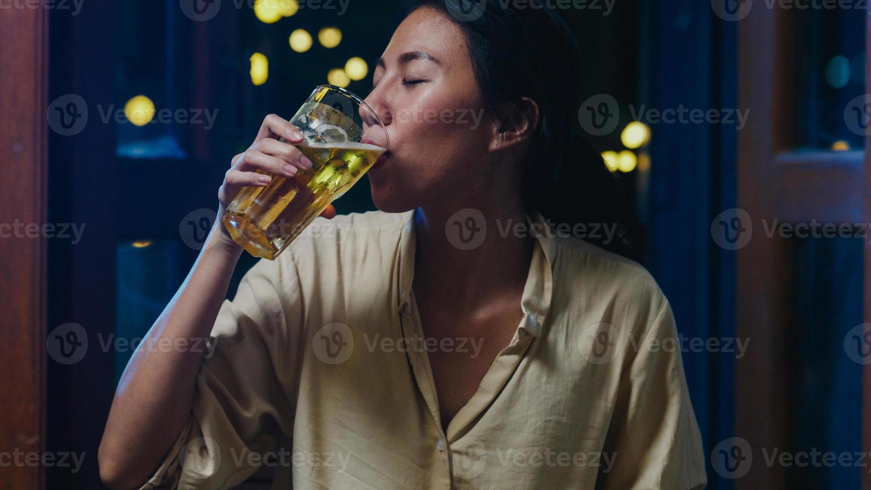 jovem asiática bebendo cerveja se divertindo feliz noite festa ano novo evento on-line celebração via videochamada por telefone em casa à noite. distância social, quarentena para coronavírus. ponto de vista ou pov foto