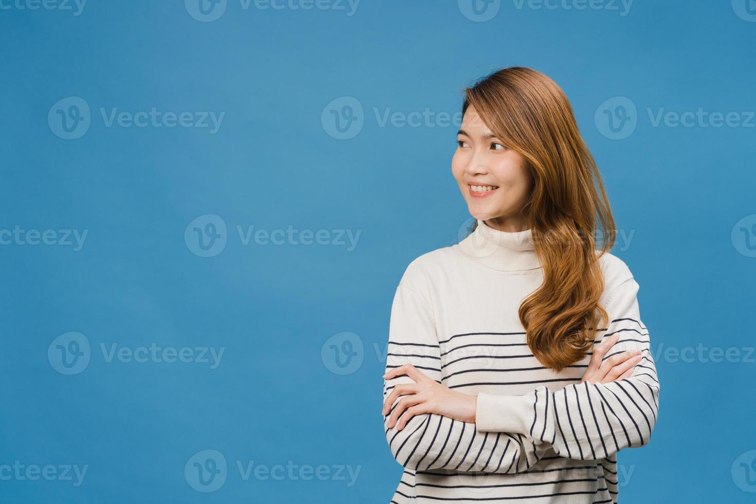 retrato de jovem asiática com expressão positiva, braços cruzados, sorriso largo, vestido com roupas casuais e olhando para o espaço sobre fundo azul. feliz adorável feliz mulher alegra sucesso. foto