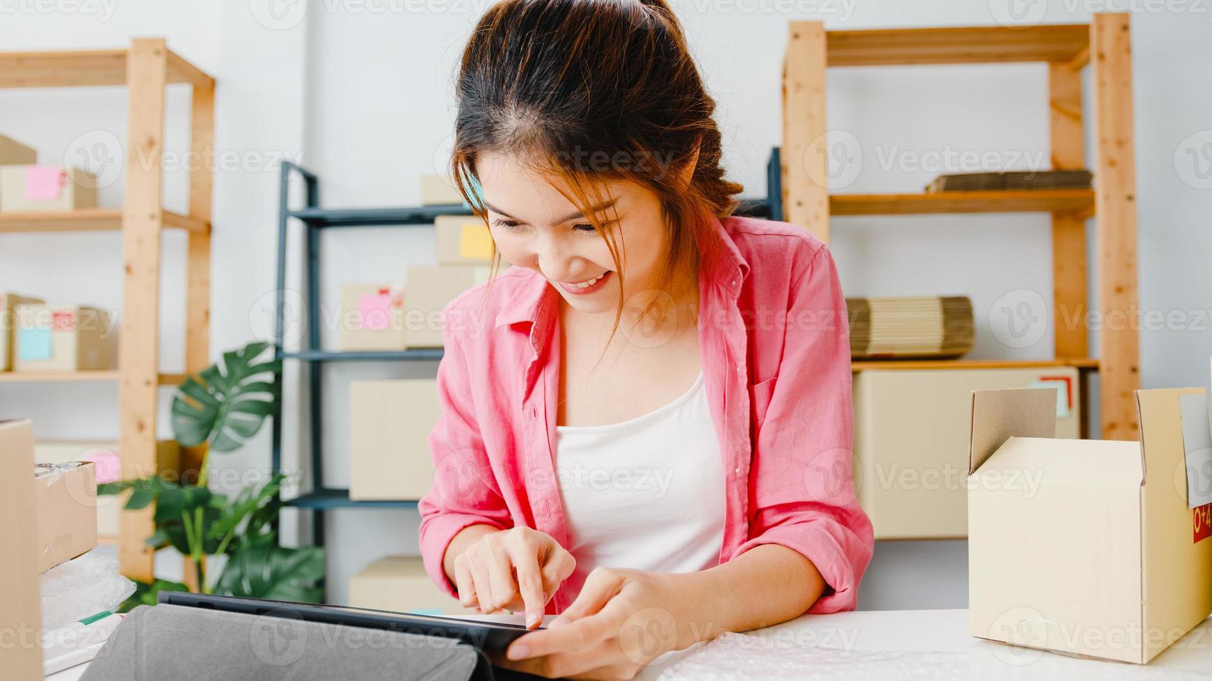 jovem ásia empresário empresária verificar o pedido de compra do produto em estoque e salvar no trabalho do computador tablet no escritório em casa. proprietário de uma pequena empresa, entrega de mercado online, conceito freelance de estilo de vida. foto