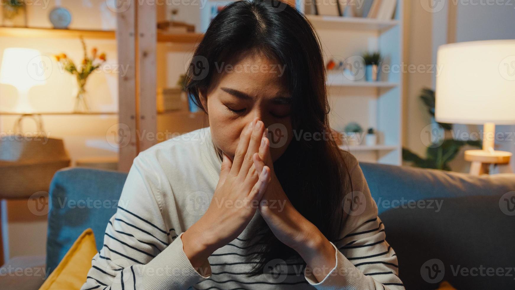 senhora asiática pensativa, sofrendo de insônia, sente-se no sofá na sala de estar à noite em casa com a sensação de solidão, adolescente deprimido e triste, passar um tempo sozinho ficar em casa, distância social, quarentena de coronavírus. foto