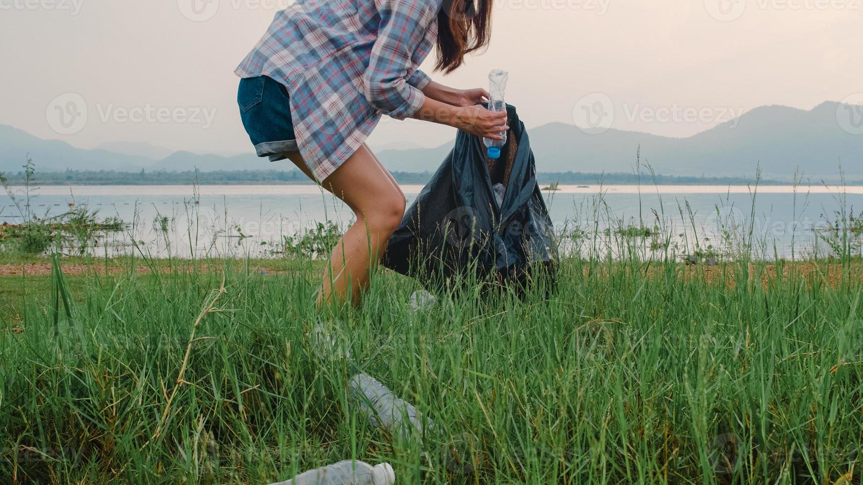 felizes jovens ativistas asiáticos que coletam lixo plástico na praia. Mulheres voluntárias coreanas ajudam a manter a natureza limpa e coletar o lixo. conceito sobre problemas de poluição de conservação ambiental. foto