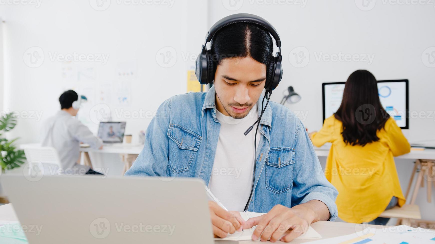 Ásia empresário distanciamento social em nova situação normal para prevenção de vírus usando laptop apresentação para colega sobre o plano de videochamada enquanto trabalha no escritório em casa. estilo de vida após o vírus corona. foto