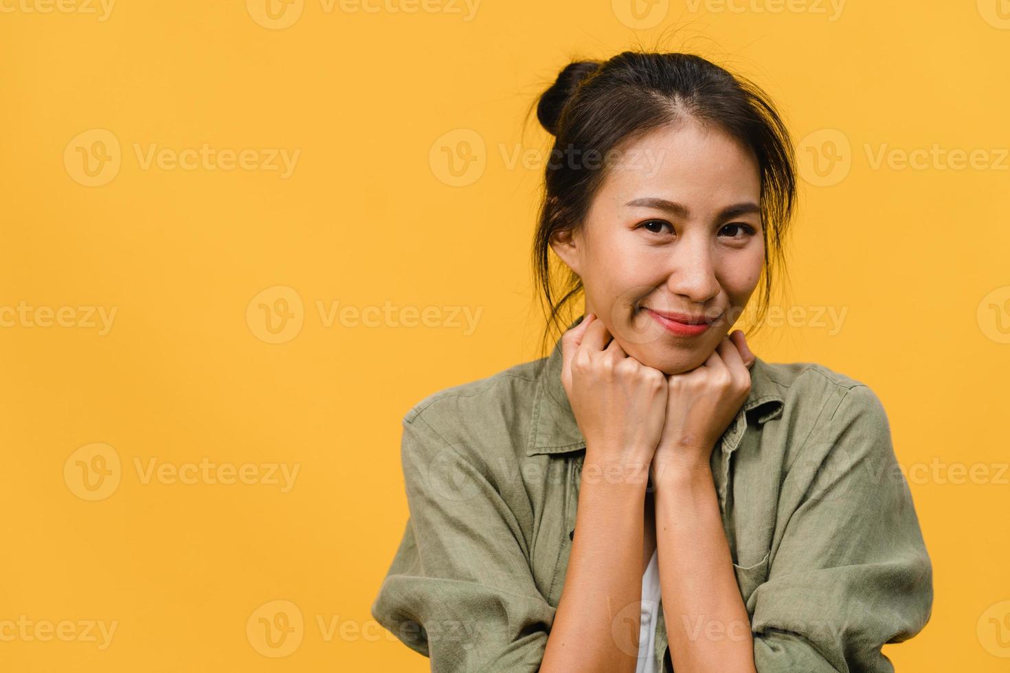 jovem asiática com expressão positiva, sorriso largo, vestida com roupas casuais e olhando para a câmera sobre fundo amarelo. feliz adorável feliz mulher alegra sucesso. conceito de expressão facial. foto