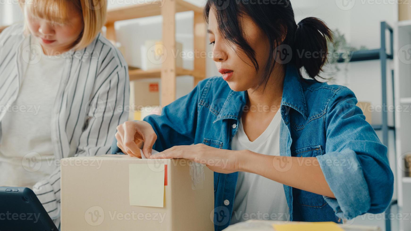 jovens empresárias da ásia usando telefone celular para receber o pedido de compra e verificar o produto no estoque trabalham no escritório em casa. proprietário de uma pequena empresa, entrega de mercado online, conceito freelance de estilo de vida. foto