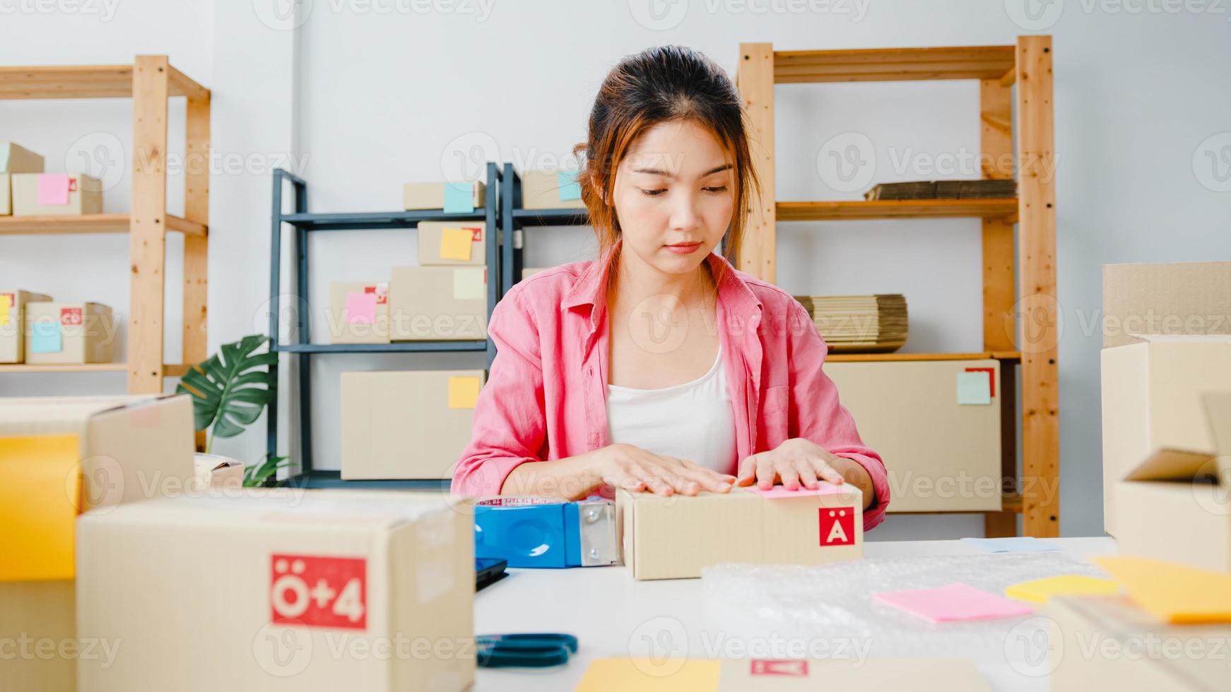 jovem ásia empresário empresária embalagem produto em caixa de papelão entregar ao cliente, trabalhando em casa. proprietário de uma pequena empresa, inicie a entrega no mercado online, conceito freelance de estilo de vida. foto