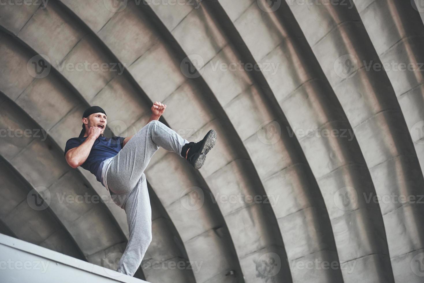 jovem fazendo parkour salto no espaço urbano na cidade ensolarada primavera dia de verão. foto