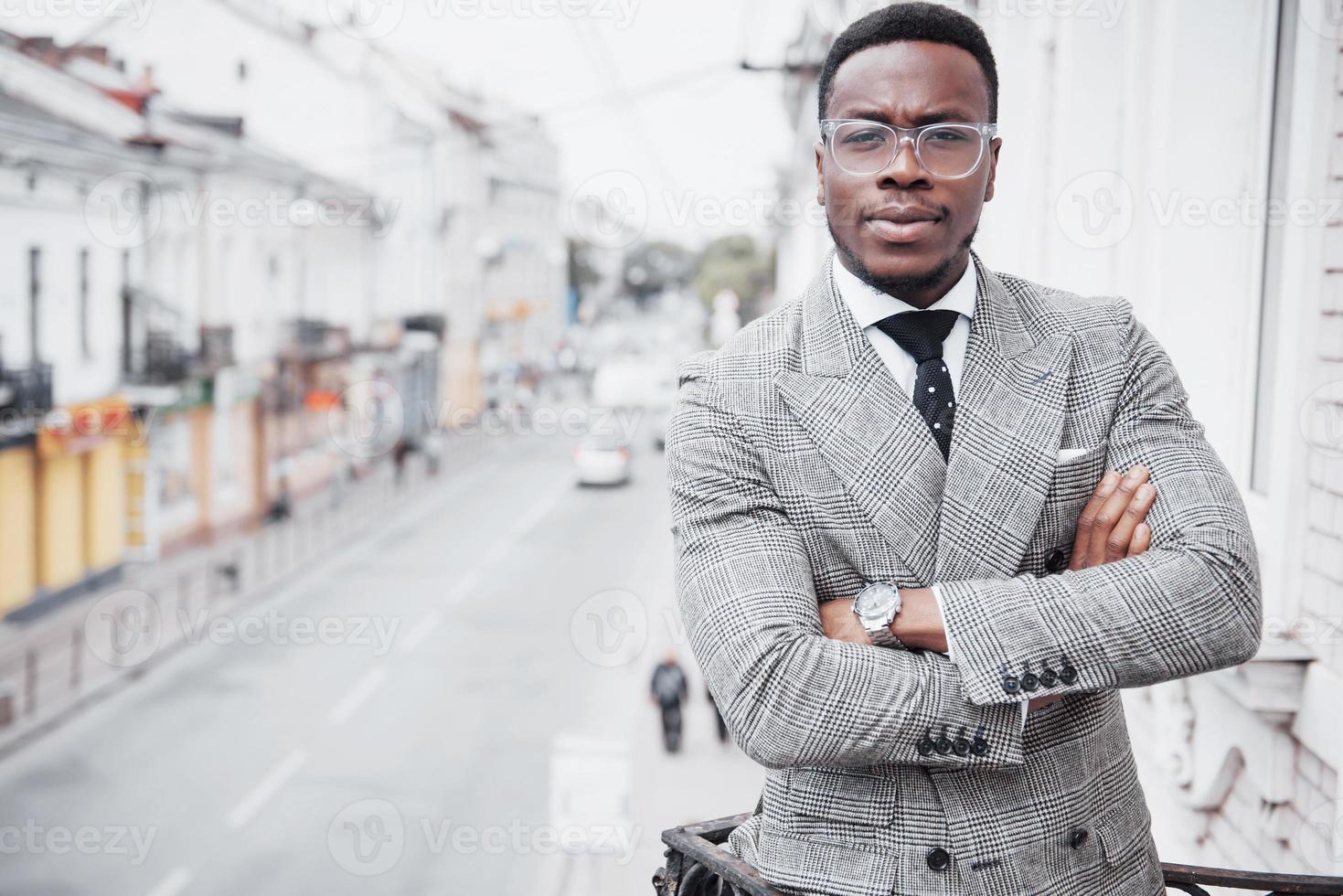 Homem de negócios negro confiante em um terno elegante em um prédio de escritórios olhando para a câmera com uma expressão séria foto