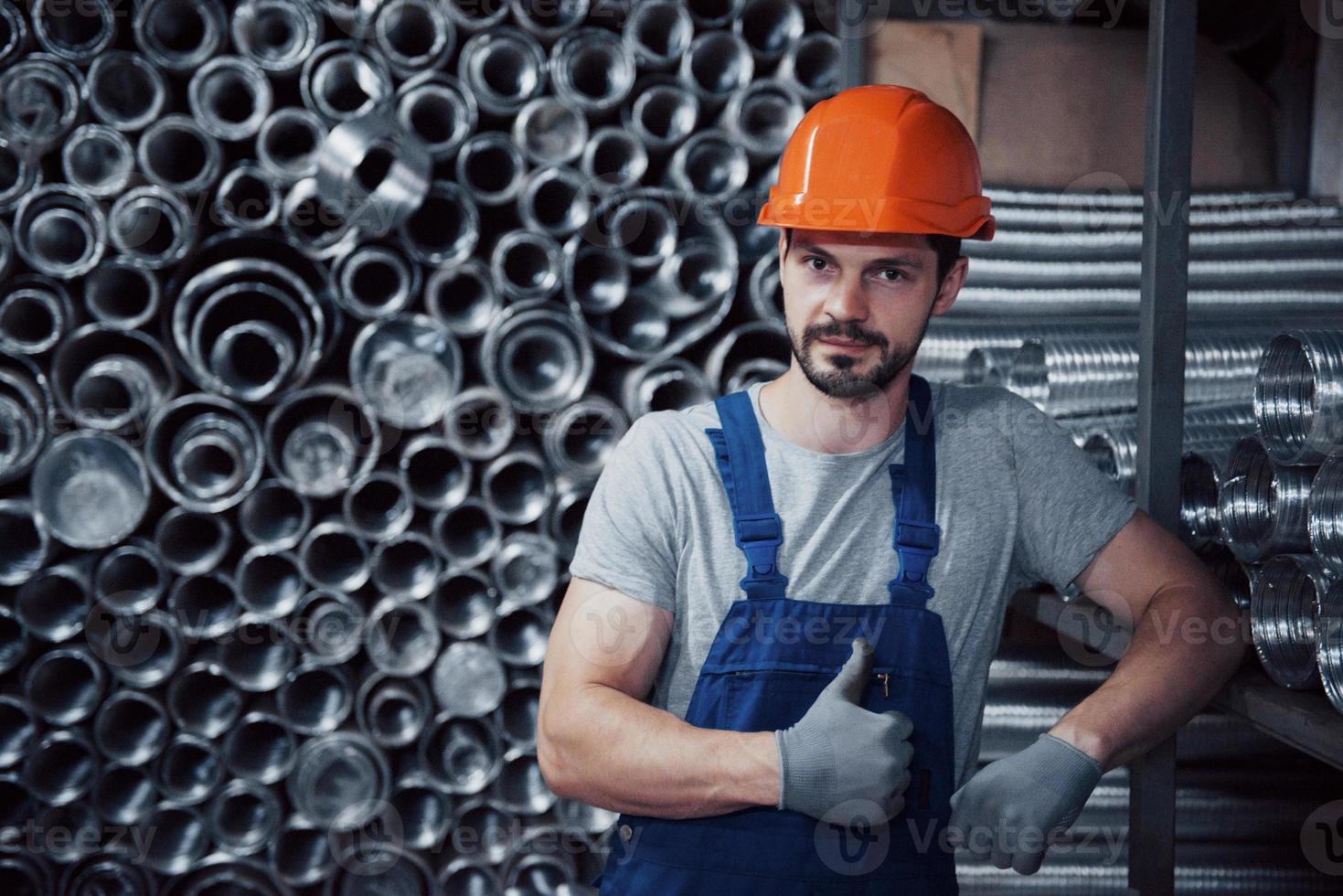 retrato de um jovem trabalhador em um capacete em uma grande usina de metais. shiftman no armazém de produtos acabados foto