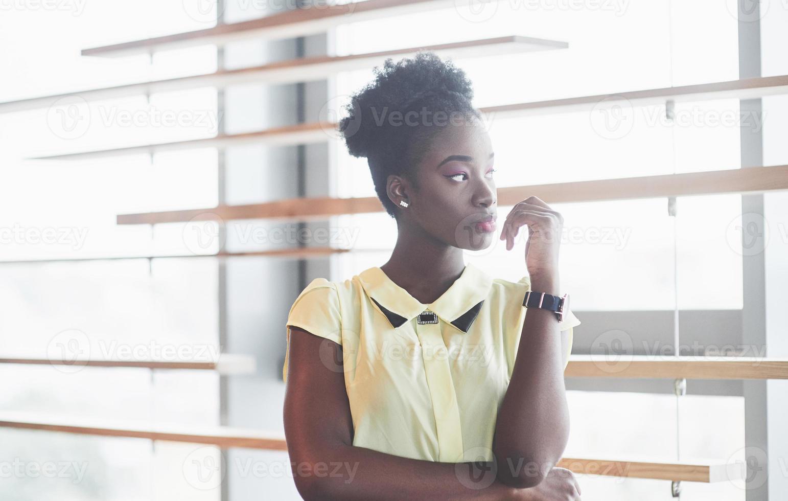 jovem garota afro-americana com cabelo escuro encaracolado pensativa em um café. lindo lugar aconchegante. foto