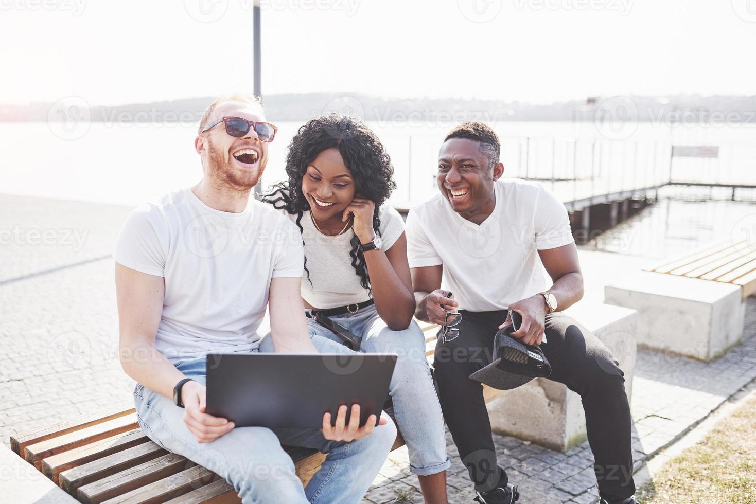 lindos amigos multi-étnicos usando um laptop na rua. conceito de estilo de vida jovem foto