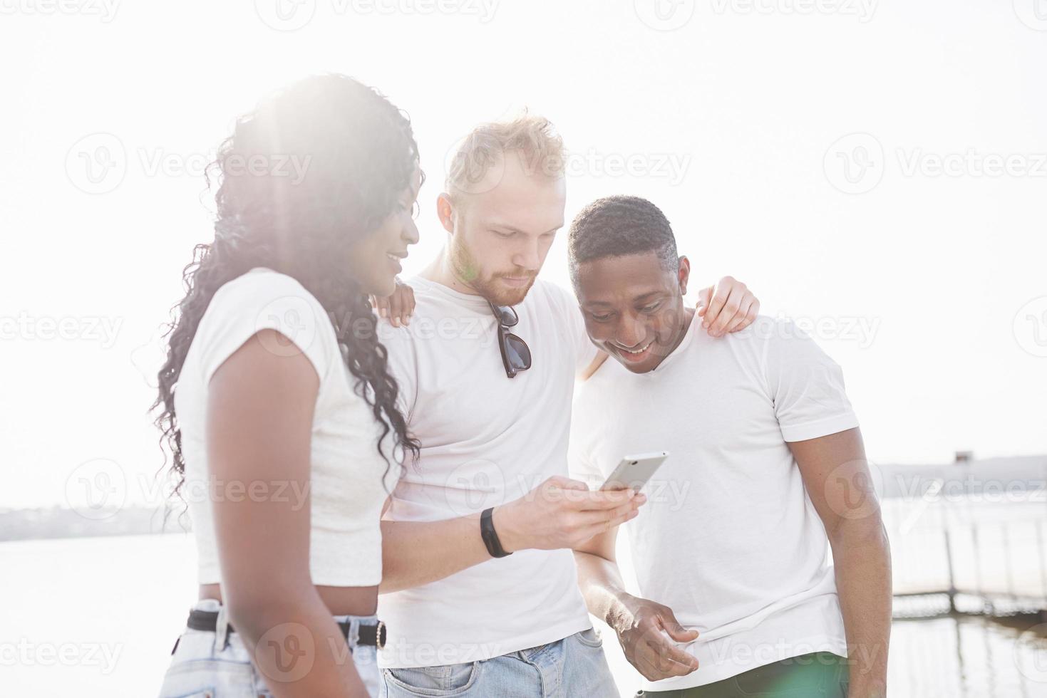 grupo de amigos multirraciais felizes usando o gadget ao ar livre. conceito de felicidade e amizade multiétnica todos juntos contra o racismo foto