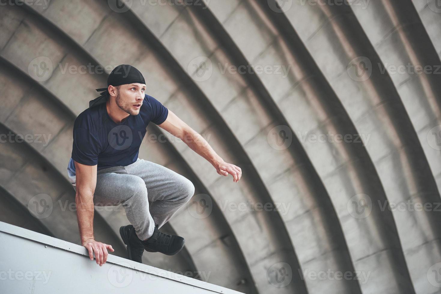 jovem fazendo parkour salto no espaço urbano na cidade ensolarada primavera dia de verão. foto