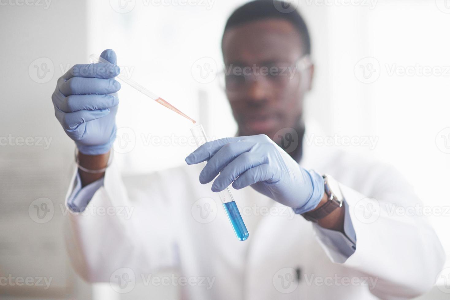 um trabalhador afro-americano trabalha em um laboratório conduzindo experimentos. foto