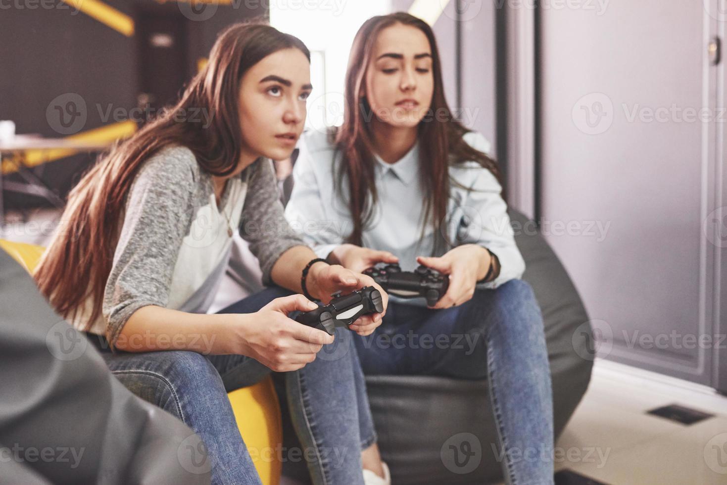 irmãs gêmeas jogam no console. meninas seguram joysticks nas mãos e se divertem foto