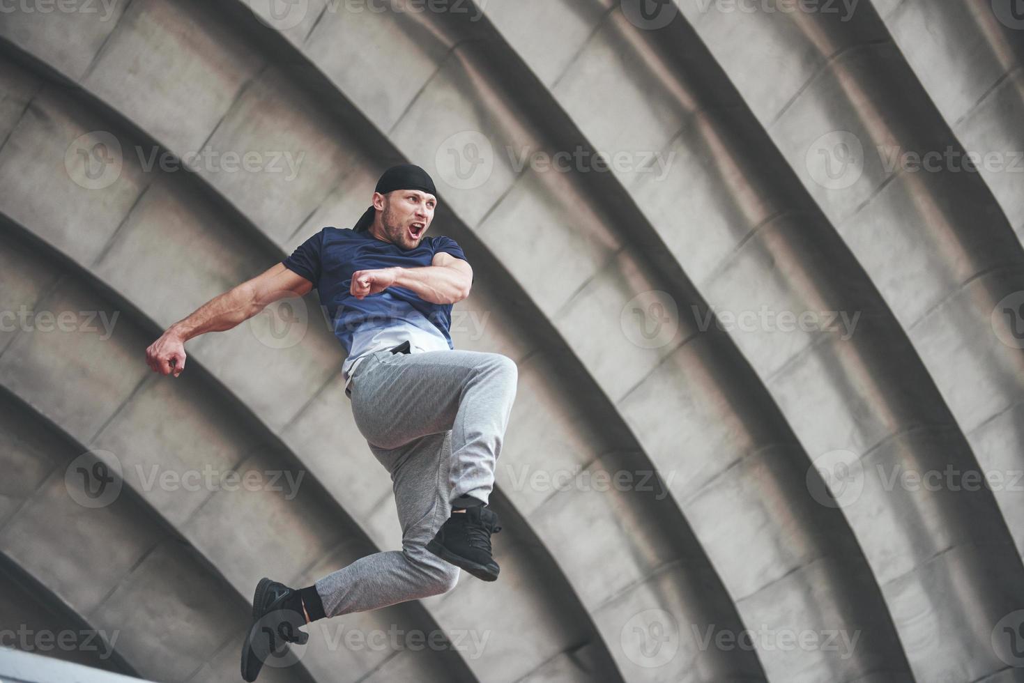 jovem fazendo parkour salto no espaço urbano na cidade ensolarada primavera dia de verão. foto