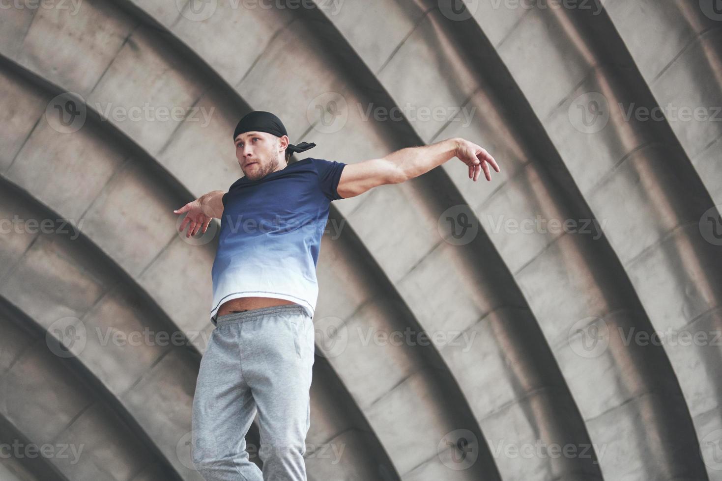 jovem fazendo parkour salto no espaço urbano na cidade ensolarada primavera dia de verão. foto