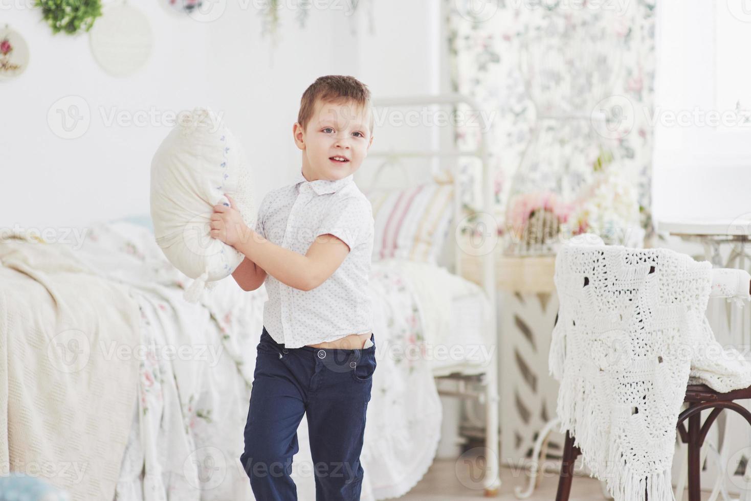 menino de camisa branca com travesseiro. luta de travesseiro foto