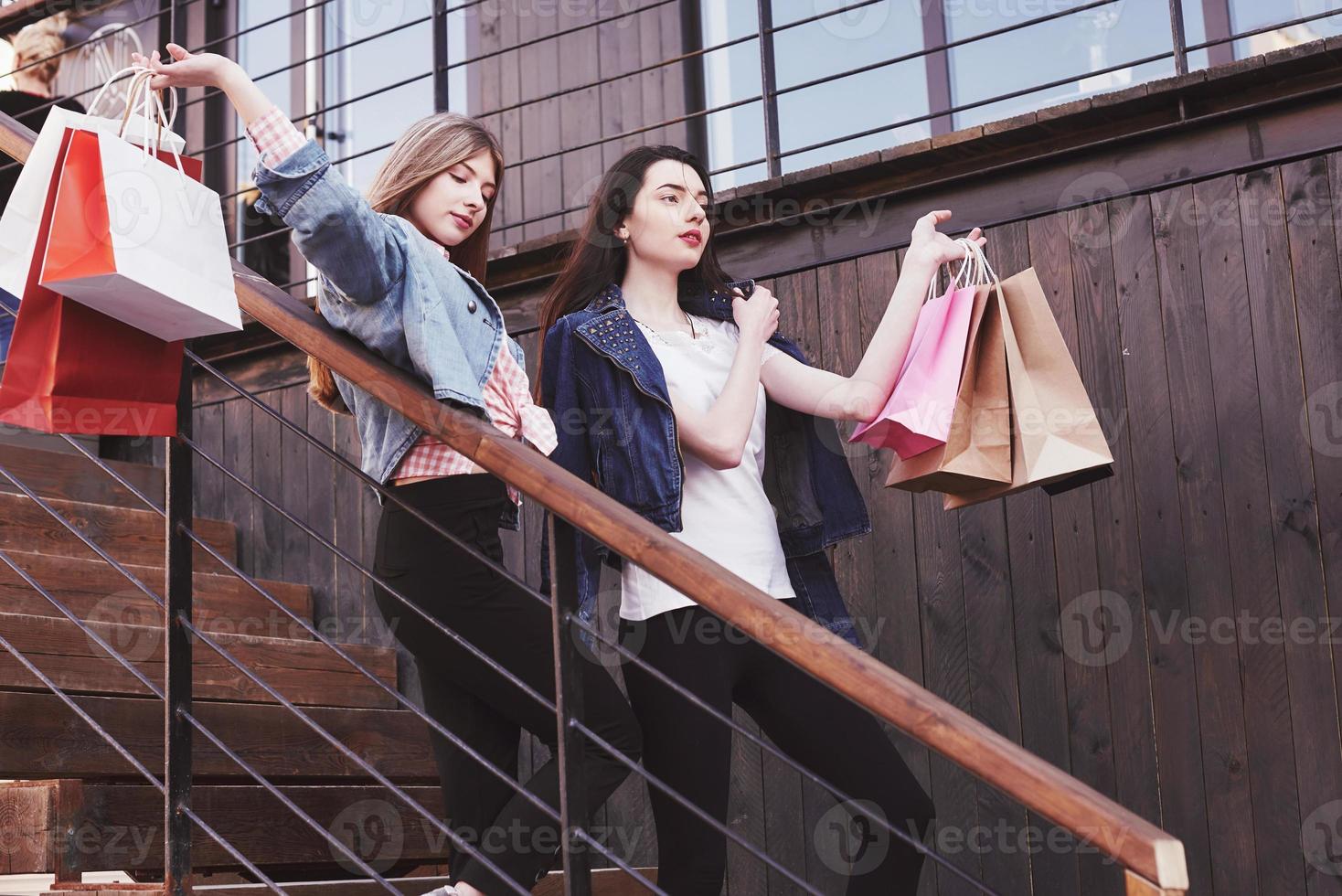 duas jovens carregando sacolas de compras enquanto caminha na escada após visitar as lojas foto